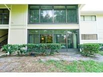 Condo exterior featuring large glass enclosed patios, trimmed shrubs, and natural surroundings at 6006 Laketree Ln # K, Temple Terrace, FL 33617