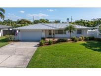 Charming single-story home featuring a well-manicured lawn, metal roof, and attached two car garage at 742 45Th Ne Ave, St Petersburg, FL 33703