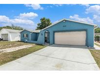 Exterior view of light blue single-story home with attached two-car garage and concrete driveway at 7426 Cay Dr, Port Richey, FL 34668