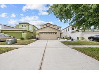 Charming two-story home with a beige exterior, a wide driveway, and well-maintained landscaping at 12107 Fox Bloom Ave, Gibsonton, FL 33534