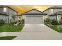 Beautiful home showcasing a well-maintained lawn, mature landscaping, and a spacious two-car garage at 20659 Drake Elm Dr, Land O Lakes, FL 34638