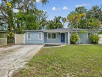 Charming single-story home with a blue exterior, well-maintained lawn, and lush trees at 232 Emerald Ln, Largo, FL 33771