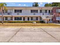 A daytime view of a two-story apartment building with ample parking, landscaping, and staircase access to the units at 2366 Shelley St # 7, Clearwater, FL 33765
