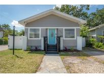 Charming bungalow featuring a bright blue front door, fresh landscaping, and updated siding at 302 W Hilda St, Tampa, FL 33603