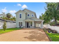 Charming two-story home featuring light green siding, gravel driveway, and a convenient covered parking area at 3505 N Dartmouth Ave, Tampa, FL 33603