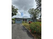 Charming single-story home with a driveway, lush lawn, and colorful flowers, creating curb appeal at 1607 Stevensons Dr, Clearwater, FL 33755