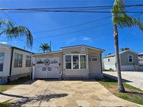 Charming tan home with a large garage door, a patterned driveway, and a bright blue sky at 2043 Ketch Cir, Palm Harbor, FL 34683