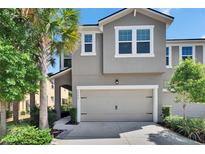 Charming townhouse featuring a two-car garage and meticulously landscaped front yard with lush greenery at 5922 Grand Sonata Ave, Lutz, FL 33558
