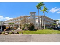Low angle view of a multi-story condo building with palm trees on a sunny day at 948 Virginia St # 202, Dunedin, FL 34698