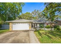Charming single-story home featuring a well-maintained lawn, stone accents, and a two-car garage, situated under a bright blue sky at 14 Idlewilde Dr, Safety Harbor, FL 34695