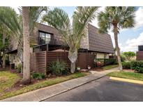 Inviting townhouse with lush landscaping, wooden fence, and unique architectural details at 15344 E Pond Woods Dr, Tampa, FL 33618