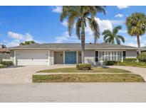 Charming single-story home with a brick driveway, lush landscaping, and a double-door entryway at 3910 Doral Dr, Tampa, FL 33634