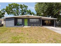 Charming single-story home featuring a well-maintained lawn and a covered carport with a bright green front door at 4311 W Oklahoma Ave, Tampa, FL 33616