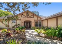 Inviting front entrance with brick archway, double doors, and lush landscaping at 4868 Lake Valencia E Blvd, Palm Harbor, FL 34684