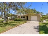 Charming single-story home with a well-manicured lawn and a brick driveway leading to an attached garage at 624 Orange St, Palm Harbor, FL 34683