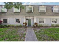Charming condo exterior with gray paint, dormer windows, green door and well-maintained landscaping at 1705 Belleair Forest Dr # B, Belleair, FL 33756