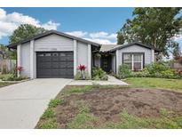 Charming single-story home with a gray exterior, a well-maintained lawn, and an attached garage at 1705 Cinnabar Ct, Brandon, FL 33510