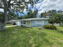 Charming single-story home with a well-maintained lawn, mature trees, and a bright yellow front door at 1713 Valencia E Dr, Largo, FL 33778