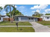Charming single-story home featuring a well-maintained lawn, gray exterior, and a welcoming white-picket fence at 4003 W Bay Ave, Tampa, FL 33616