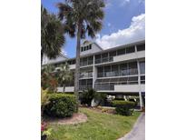 Multi-story condo building featuring screened balconies and lush landscaping with palm trees at 5557 Sea Forest Dr # 216, New Port Richey, FL 34652