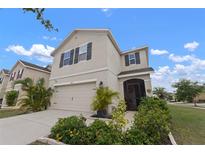 Two story home with neutral paint, dark shutters, landscaping and a two car garage at 10101 Mangrove Well Rd, Ruskin, FL 33573