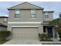Two-story home featuring a neutral gray exterior, a two-car garage, and well-maintained landscaping at 14812 Boulder Pass Pl, Wimauma, FL 33598