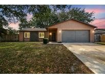 Charming single-story home featuring a gray garage door and a well-maintained lawn at 16039 Frost Dr, Hudson, FL 34667