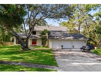 Charming two-story home with a three-car garage, mature trees, and manicured lawn at 1800 Salem Ct, Dunedin, FL 34698
