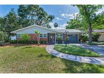 Charming single-story brick home with a landscaped yard, walkway, and gray garage door at 202 S Hesperides St, Tampa, FL 33609
