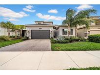 Beautiful one-story home featuring a two-car garage, stone accents and lush landscaping at 3096 Great Banyan Way, Wesley Chapel, FL 33543
