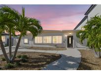 Charming home exterior with tropical landscaping, walkway, and neutral paint at twilight at 3210 E Maritana Dr, St Pete Beach, FL 33706
