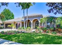 Beautifully landscaped home with a well-manicured lawn, arched entrance, and a spacious three-car garage at 3212 Sunset Lakes Blvd, Land O Lakes, FL 34638