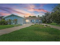 Charming home with a well-manicured lawn, circular driveway, and delightful landscaping under a colorful sunset at 5053 43Rd S St, St Petersburg, FL 33711
