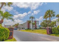 Low-angle shot of a condominium complex with tropical landscaping and mature palm trees at 5575 Gulf Blvd # 329, St Pete Beach, FL 33706