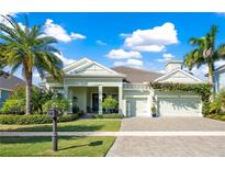 Charming home with a well-manicured lawn, mature palm trees, and a paver driveway leading to a two-car garage at 716 Manns Harbor Dr, Apollo Beach, FL 33572
