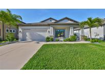 Charming single-story home features a well-manicured lawn, lush landscaping, and a two-car garage at 11407 Leland Groves Dr, Riverview, FL 33579