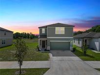 Charming two-story home with a well-manicured lawn and a two-car garage at sunset at 11530 Adam Lee Way, Dade City, FL 33525