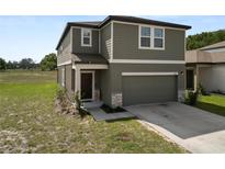 Inviting two-story house featuring neutral paint, a two-car garage, and a neatly landscaped front yard at 11530 Adam Lee Way, Dade City, FL 33525