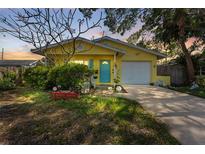 Charming yellow single-story home features a lovely blue front door and an attached one car garage at 1782 Maryland Ne Ave, St Petersburg, FL 33703