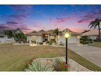 Inviting single-story home featuring a tile roof, two-car garage, manicured lawn, and mature palm trees at 2017 S Pebble Beach Blvd, Sun City Center, FL 33573