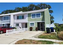 Townhouse with a light green exterior, white trim, a well kept front yard, and a gray roof at 2751 S Pines Dr # 10, Largo, FL 33771