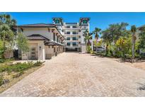Elegant building featuring a long brick driveway with tropical landscaping and convenient covered parking at 455 Pinellas Bayway S # 4A, Tierra Verde, FL 33715