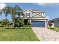 Inviting two-story home with a blue garage door, lush lawn, and well-manicured landscaping, creating great curb appeal at 879 De Soto Blvd, Tarpon Springs, FL 34689