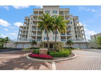 Luxury high-rise condo building with elegant architecture, lush landscaping and circular brick driveway entrance at 145 Belleview Blvd # 201, Belleair, FL 33756
