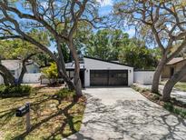 Charming renovated home with modern garage doors and mature landscaping offering great curb appeal at 2257 Lake Dr, Dunedin, FL 34698