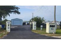 Property entrance featuring a long driveway, steel building, black iron fence and decorative entrance posts at 3302 W Shell Point Rd, Ruskin, FL 33570