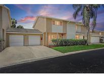 Charming townhouse featuring a two-car garage, well-maintained landscaping, and inviting curb appeal under a beautiful sunset sky at 6490 Cape Hatteras Ne Way # 4, St Petersburg, FL 33702