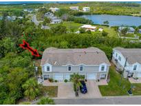 Three-story townhouse with attached garages and a well-maintained front yard in a lush, green setting at 7647 Navigator Ct, Port Richey, FL 34668