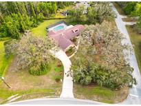 A sprawling single-Gathering home features mature landscaping, a long driveway, and an in-ground pool with screened enclosure at 10206 Lakeview Dr, New Port Richey, FL 34654