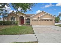 Charming single-story home featuring a three-car garage, manicured lawn, and inviting front entrance at 10322 Riverburn Dr, Tampa, FL 33647